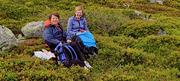 Viser to personer sittende i lyngen.